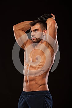 Strong man making exercises on triceps with a dumbbell. Close up shot training hands. Fitness Model showing his Torso
