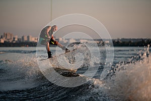 strong man masterfully jumping on splashing wave on a wakeboard