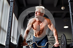 Strong man with muscular body working out in gym. Weight exercise with barbell in fitness club.