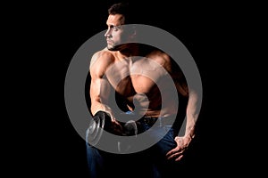 Strong man with muscular body working out. Weight exercise with dumbbell on black background.