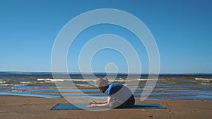 Strong man practicing difficult yoga pose on the beach