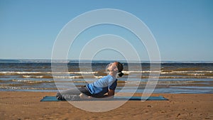 Strong man practicing difficult yoga pose on the beach