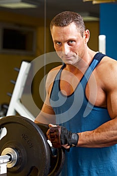 Strong man preparing his training machine in fitness