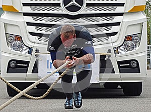 A strong man pulls a big truck