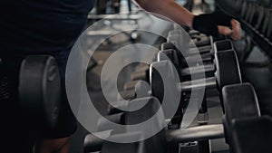 Strong man`s hand takes a heavy dumbbell in gym, close up macro indoor sport guy