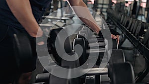 Strong man`s hand takes a heavy dumbbell in gym, close up macro indoor sport guy