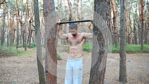 Strong man showing some exercises on horizontal bar. Muscular guy doing pull ups. Athlete performs strength workout in