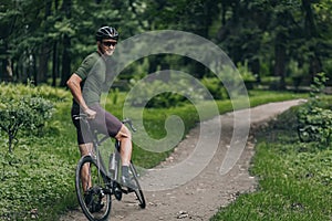 Strong man sitting on bike and smiling on camera outdoors