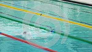 Strong man swimming front crawl in pool, slow motion. Perseverance, fortitude