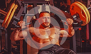 Strong man is training in the gym. Muscular man workout with barbell at gym. Bodybuilder athletic man with six pack