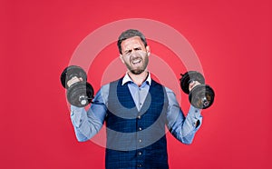Strong manager in formal style lifting heavy dumbbells red background, strength