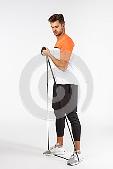 Strong masculine handsome sportsman in football activewear, standing full-length perform workout exercise with equipment