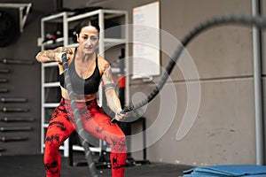 Strong mature woman working out with battle ropes