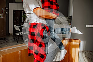 Strong man carrying his woman in the room with boxes