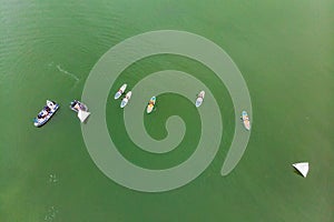 Strong men floating on a SUP boards in a beautiful bay on a sunny day. Aerial view of the men crosses the bay using the