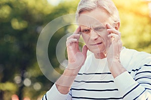 Sad cheerless man holding his temples