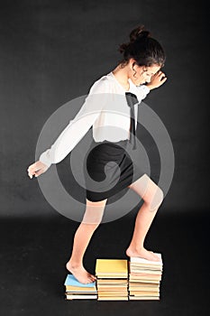 Strong-minded teenage girl balancing on top of old books