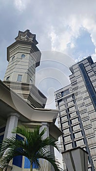 Strong Mosque Tower and Great Skyscraper Building with Cloudly Blue Sky