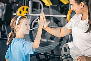 Strong mother and daughter giving high five at gym.