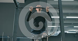 strong motivated disabled man pulling up on horizontal bar in a gym