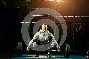 Strong motivated muscular bodybuilder man holding a heavyweight barbell