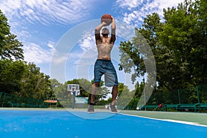 Strong muscular african-american male basketball player training at street public stadium, sport court or palyground