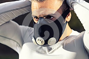 Strong muscular athlete putting on his fitness breathing mask and getting ready for a workout