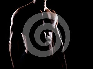 Strong and muscular body of man shaded over black background photo