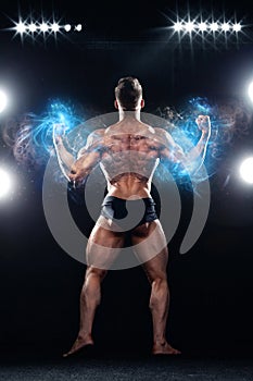Strong muscular bodybuilder athlete man posing and pumping up muscles on black background. Workout bodybuilding concept.