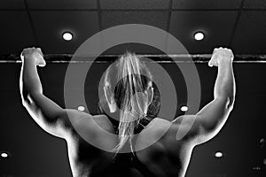 Strong muscular female doing pull up in gym