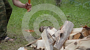 A strong muscular guy chopping wood in a birch forest.