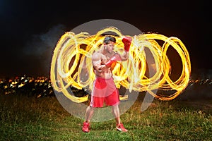 Strong muscular male fighter with fire and flames behind his bac