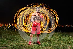 Strong muscular male fighter with fire and flames behind his bac