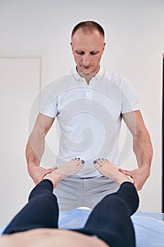 Strong muscular male reflexologist helping unrecognized woman with exercises in rehabilitation center