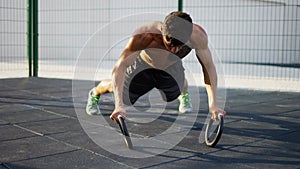 Strong, muscular man is doing push-ups by rings