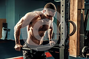 Strong muscular man doing push-ups on uneven bars in crossfit gym