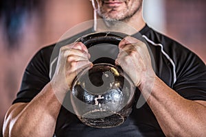 Strong muscular man exercising with kettlebell facilities in gym