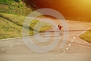 Strong muscular man riding his racing bike on a mountain road through hills