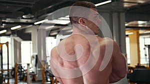 Strong muscular shirtless man in front of mirror in a gym