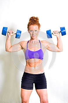 Strong muscular young woman lifting weights