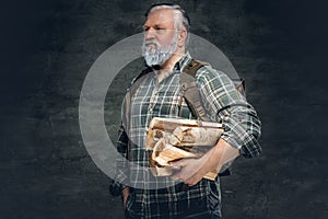 Strong old man with bag and stack of lumber against dark background