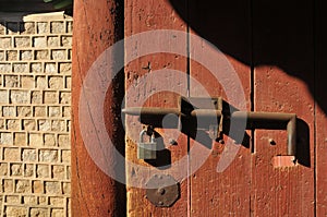 Strong old secured metal lock on traditional ancient wooden door of old Korean stone wall in the afternoon