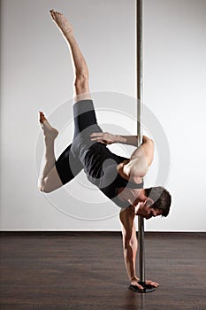 Strong pole dancer smiling man in black clothes on pylon. White background