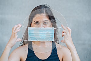 Strong portrait of young woman with protective surgical face mask. Protection against COVID-19