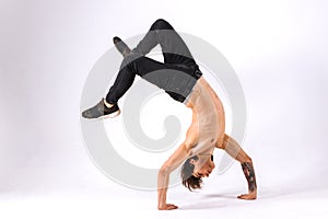 Strong powerful boy, man - freerunner, acrobat, tricker with muscular body in a jump upside down on a white background