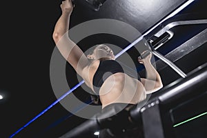 A strong and powerful female athlete effortlessly does a set of pullups. Possessing a well developed upper back