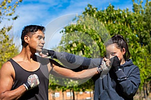 Strong and powerful young woman professional boxing athlete engaged with her personal trainer on the street during preparation for