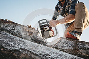 Strong professional lumberman use chainsaw on sawmill