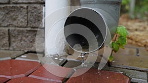 Strong rain water flowing out from rain grey drain pipe on a building wall