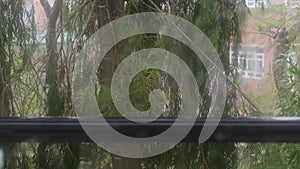 Strong rain water flushes against window glass and streaming down. Close-up. Raindrops on glass background in rainy